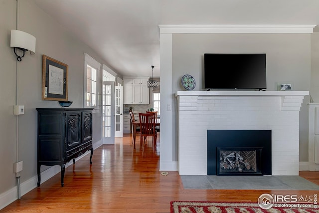 living area with light wood-style floors, baseboards, and a fireplace
