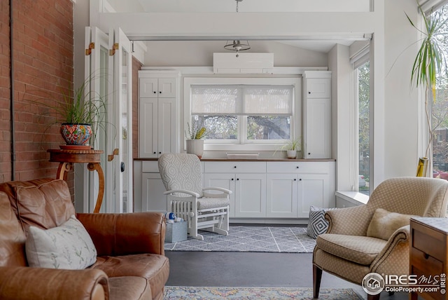 sitting room featuring vaulted ceiling and concrete flooring