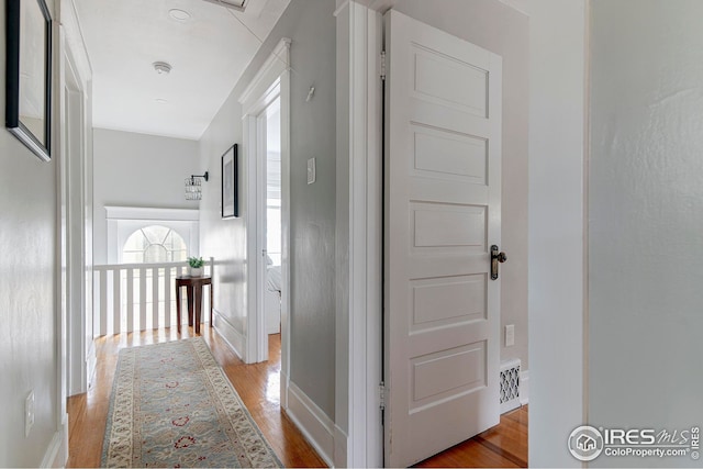 corridor with baseboards, visible vents, and wood finished floors
