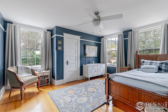 bedroom with baseboards, multiple windows, ceiling fan, and light wood-style flooring