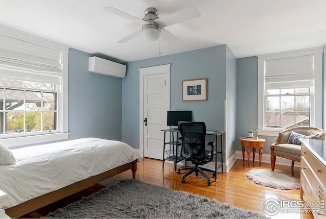 bedroom with baseboards, a ceiling fan, a wall mounted air conditioner, and wood finished floors