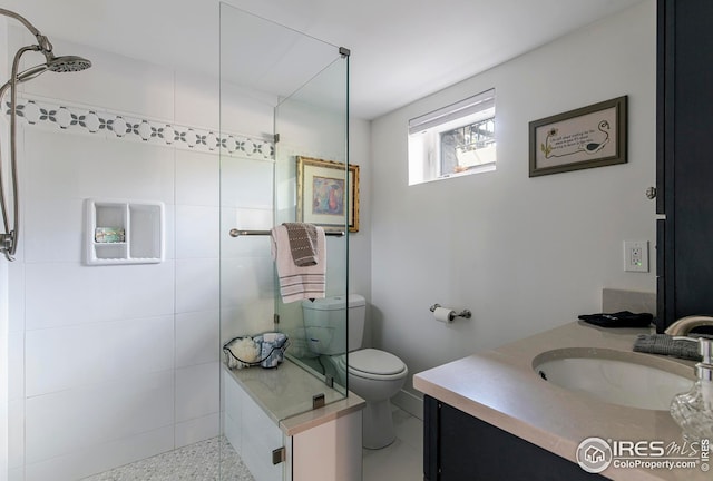 full bath with toilet, tiled shower, and vanity