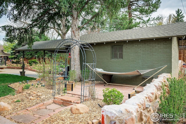 exterior space with brick siding and a shingled roof
