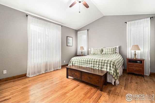 bedroom with light wood-style floors, baseboards, a ceiling fan, and vaulted ceiling