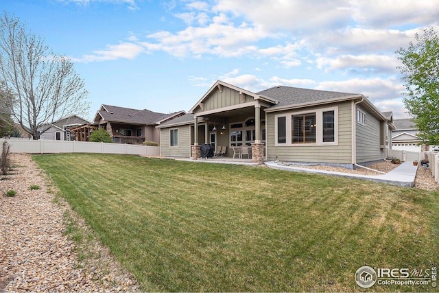 rear view of property with a fenced backyard, a lawn, and a patio area