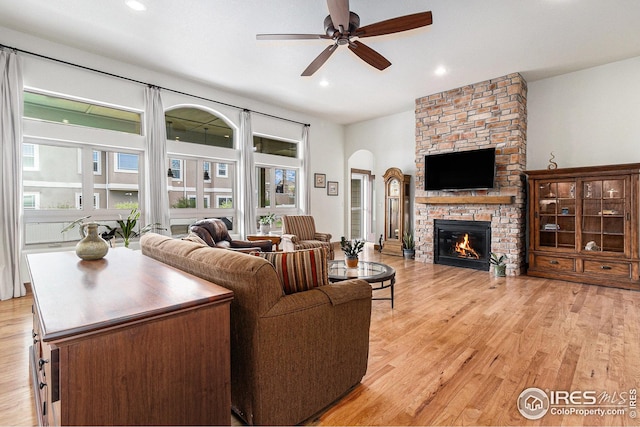 living room with arched walkways, a ceiling fan, a wealth of natural light, and light wood-style floors