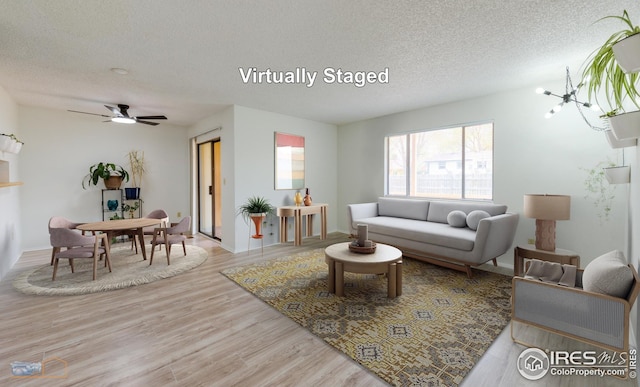 living area with a ceiling fan, a textured ceiling, and wood finished floors