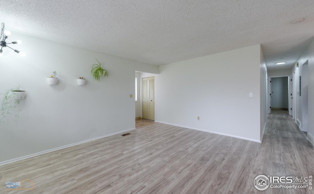 unfurnished room with baseboards, a textured ceiling, and light wood-style flooring