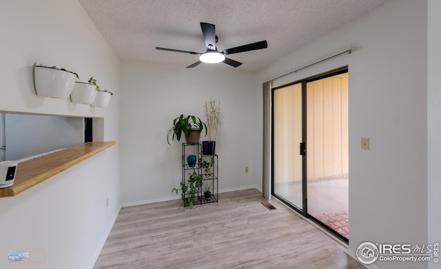 sitting room with baseboards, a ceiling fan, a textured ceiling, and wood finished floors