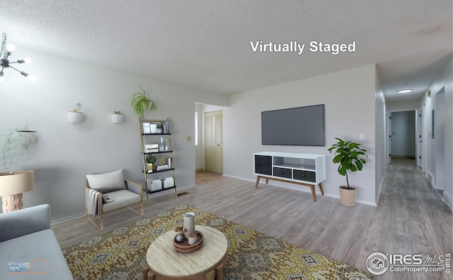 living room featuring baseboards, a textured ceiling, and wood finished floors