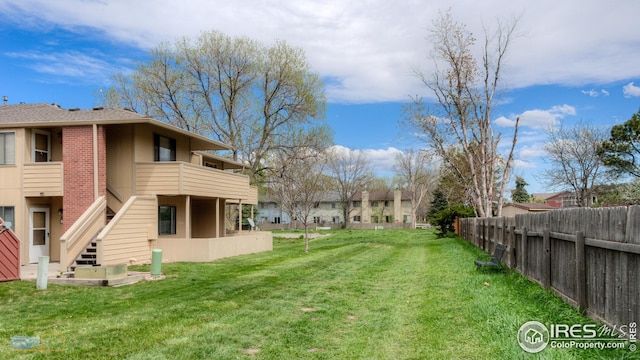 view of yard featuring stairs, fence, and a balcony