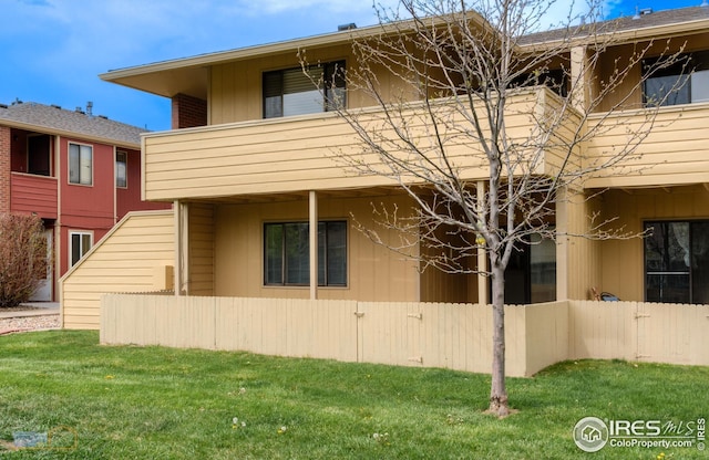 view of side of property featuring a lawn, fence, and a balcony