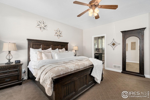 carpeted bedroom featuring a ceiling fan, baseboards, visible vents, and ensuite bath