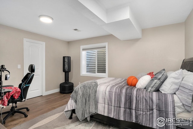 bedroom with visible vents, baseboards, and wood finished floors