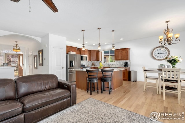 living area with recessed lighting, arched walkways, light wood finished floors, and a notable chandelier