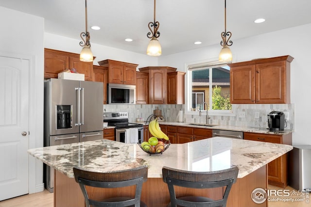 kitchen featuring appliances with stainless steel finishes, a sink, a kitchen breakfast bar, a center island, and decorative backsplash