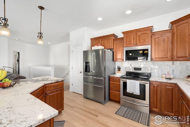 kitchen with backsplash, appliances with stainless steel finishes, light stone countertops, brown cabinets, and light wood-style flooring