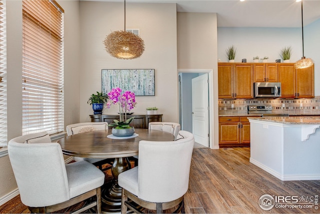 dining area featuring a high ceiling, wood finished floors, and visible vents