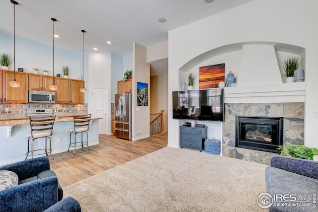 living area with visible vents, a towering ceiling, a fireplace, light wood-type flooring, and recessed lighting