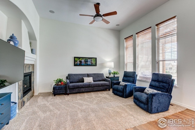living area with baseboards, a ceiling fan, wood finished floors, and a tile fireplace
