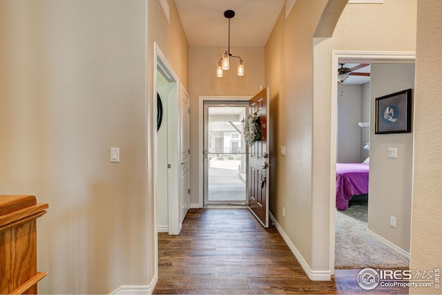 entryway featuring arched walkways, baseboards, dark wood-style flooring, and ceiling fan