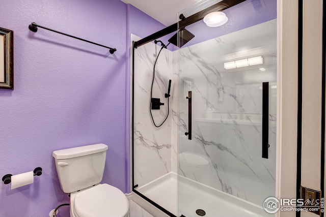 full bathroom with toilet, a textured wall, and a marble finish shower