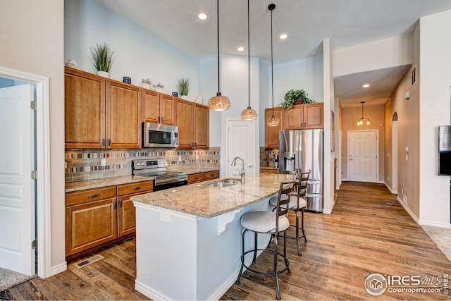 kitchen featuring a sink, appliances with stainless steel finishes, backsplash, and brown cabinets