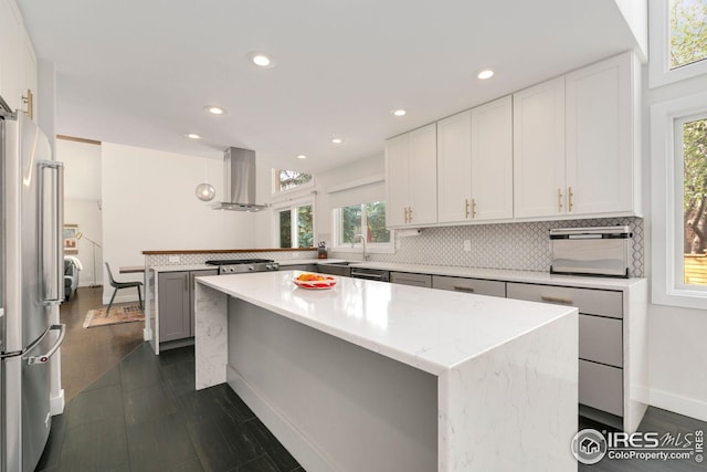 kitchen featuring wall chimney exhaust hood, freestanding refrigerator, a peninsula, recessed lighting, and tasteful backsplash