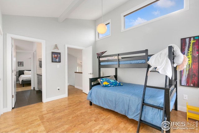 bedroom with baseboards, beam ceiling, and wood finished floors