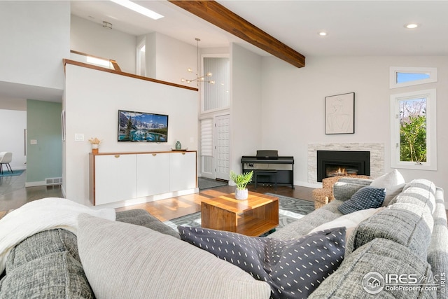 living area with a high ceiling, a notable chandelier, beam ceiling, recessed lighting, and visible vents