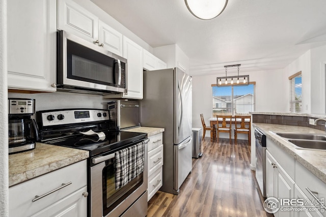 8596 Seattle Slew Ln, Wellington, CO 80549 - kitchen featuring wood finished floors, light countertops, white cabinets, a sink, and appliances with stainless steel finishes