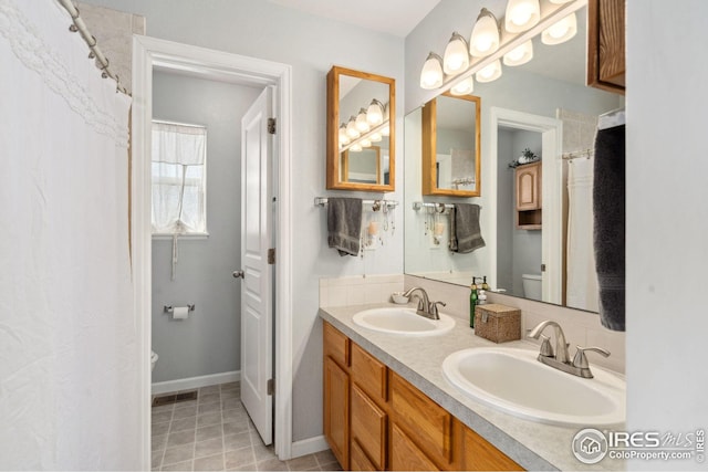 8596 Seattle Slew Ln, Wellington, CO 80549 - bathroom with double vanity, toilet, baseboards, and a sink