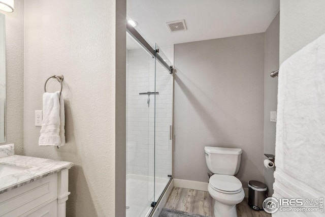 8596 Seattle Slew Ln, Wellington, CO 80549 - full bath featuring visible vents, vanity, wood finished floors, toilet, and a stall shower