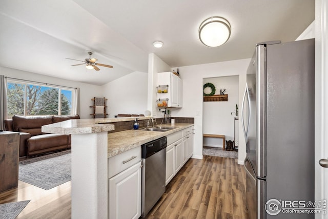 8596 Seattle Slew Ln, Wellington, CO 80549 - kitchen with white cabinets, a sink, stainless steel appliances, open floor plan, and a peninsula