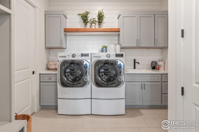 laundry room with a sink, light tile patterned floors, washing machine and dryer, and cabinet space