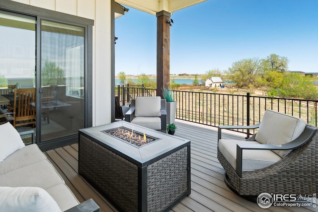 balcony featuring a deck with water view and an outdoor living space with a fire pit