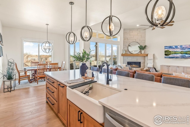 kitchen with brown cabinetry, a sink, plenty of natural light, and a stone fireplace