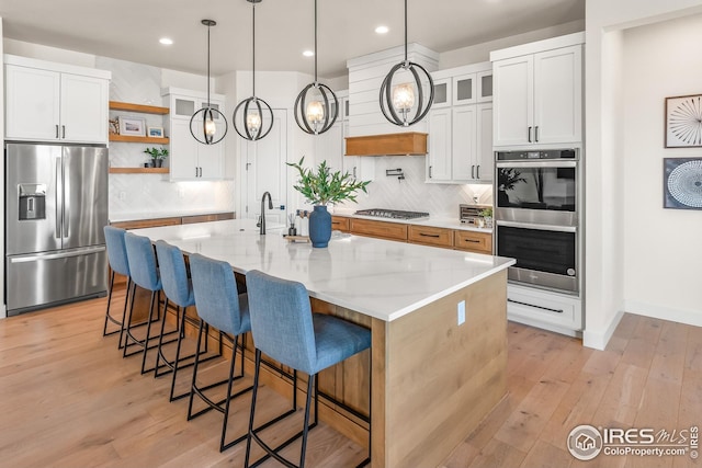 kitchen featuring backsplash, open shelves, appliances with stainless steel finishes, and light wood-style floors