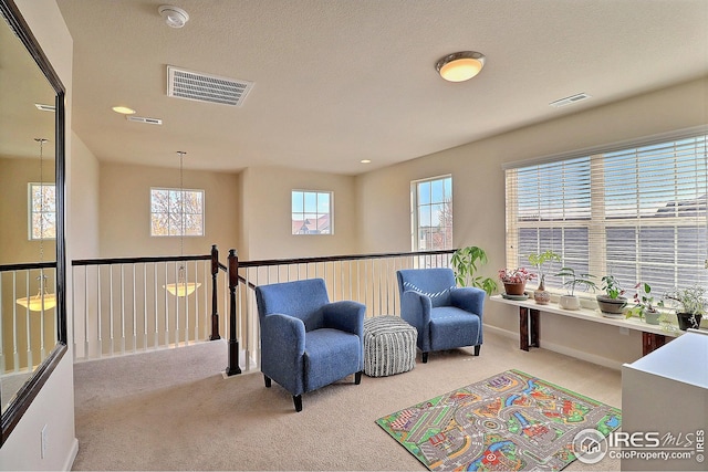 living area featuring carpet floors, visible vents, and an inviting chandelier