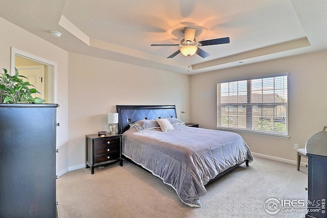 bedroom featuring baseboards, light carpet, ceiling fan, and a raised ceiling
