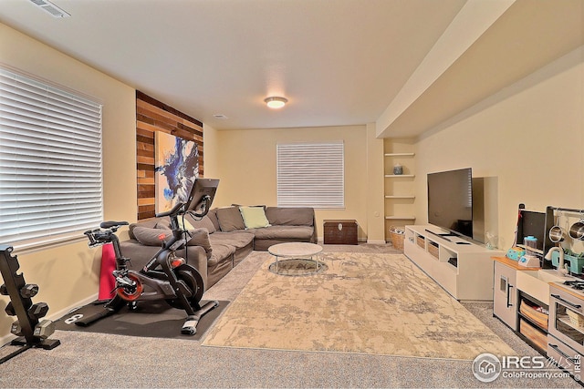 carpeted living room with built in features, baseboards, and visible vents