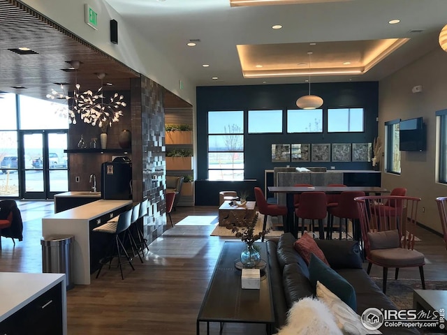 living area with french doors, recessed lighting, a tray ceiling, and wood finished floors