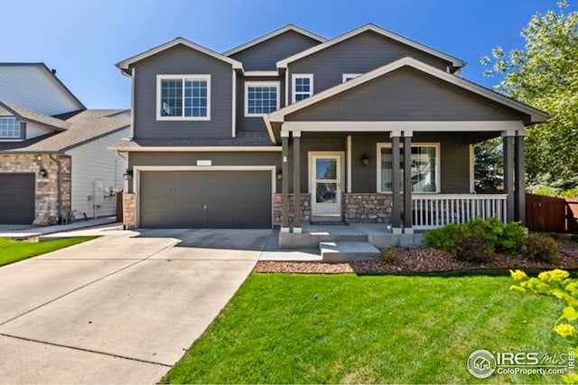 craftsman inspired home featuring an attached garage, a front lawn, stone siding, concrete driveway, and covered porch