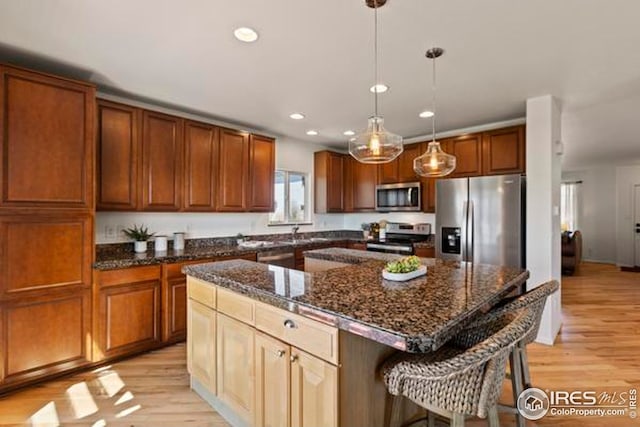 kitchen with light wood-style floors, recessed lighting, appliances with stainless steel finishes, and a kitchen breakfast bar