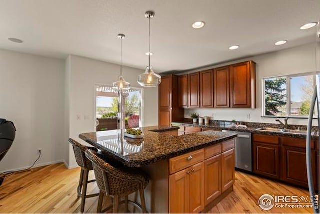 6117 Gold Dust Rd, Timnath, CO 80547 - kitchen with dishwasher, light wood-style floors, a kitchen breakfast bar, recessed lighting, and decorative light fixtures