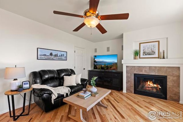 living area featuring a fireplace, a ceiling fan, and wood finished floors