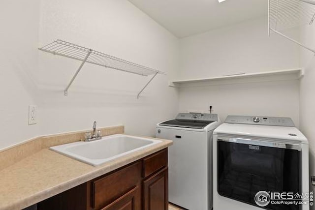 laundry area featuring washing machine and clothes dryer, a sink, and cabinet space