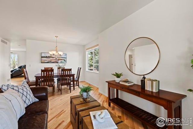 living area featuring a chandelier, a wealth of natural light, and light wood-style flooring