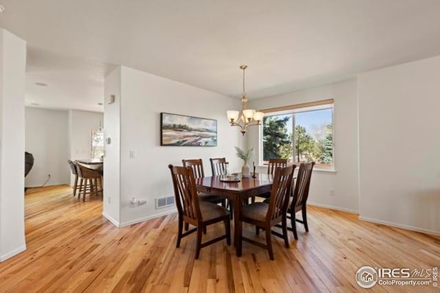 dining room featuring visible vents, light wood-style flooring, baseboards, and a chandelier