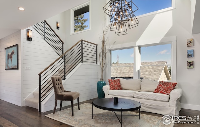 living room featuring wood walls, stairs, a high ceiling, dark wood-type flooring, and recessed lighting